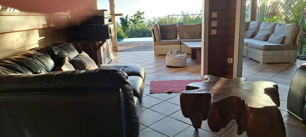 Au rez-de-jardin, la vie s'articule entre l'intérieur chaleureux et la terrasse, offrant un accès direct à la piscine et aux senteurs du jardin tropical à la Villa Secret Garden Pointe-Noire Guadeloupe